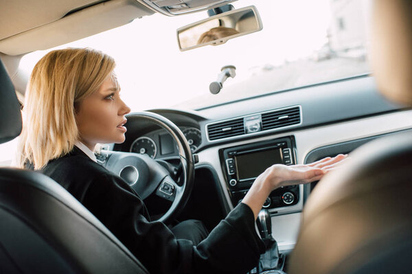upset blonde woman gesturing while sitting in car 