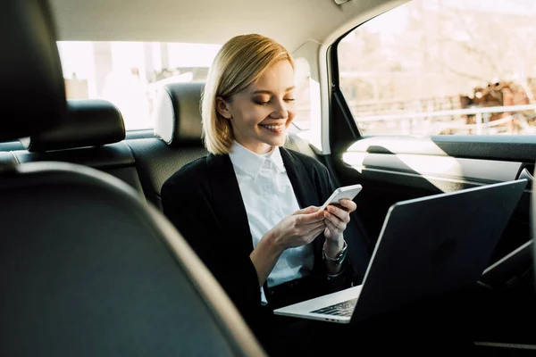 Fröhliche Blonde Junge Frau Blickt Aufs Smartphone Und Lächelt Auto — Stockfoto