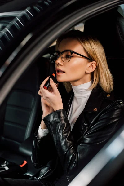 Gyönyörű Szőke Lány Szemüveg Alkalmazása Rúzs Autóban — Stock Fotó