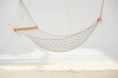 hanging hammock made of net over sand on grey clipart