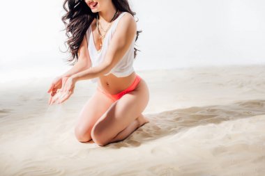 elleri ile düşen kum ile sahilde oturan kız kırpılmış görünümü