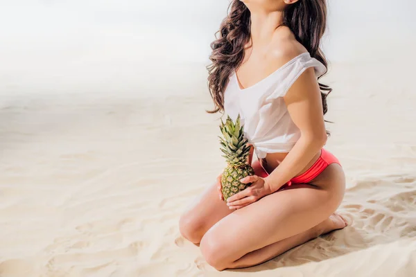 Обрезанный Вид Девушки Сидящей Позирующей Ананасом Песчаном Пляже — стоковое фото