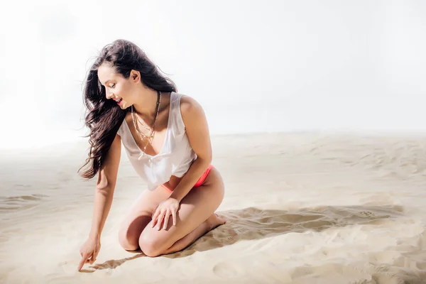 Красива Дівчина Малює Пальцем Піску Сидячи Пляжі Копіювальним Простором — стокове фото