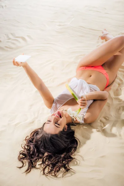 Hermosa Chica Sacando Lengua Acostado Playa Con Flor Tomando Selfie —  Fotos de Stock