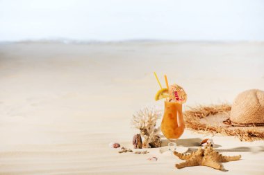 cocktail, starfish, Straw Hat, coral and sea stones on sandy beach with copy space