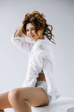 neşeli genç kadın oturan ve beyaz kıvırcık kırmızı saç dokunmadan 