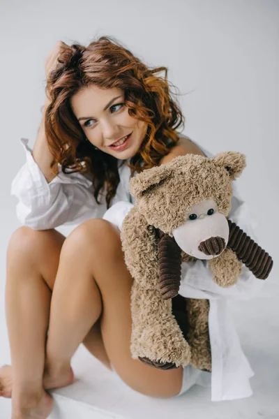 Happy Curly Young Woman Holding Teddy Bear While Touching Hair — Stock Photo, Image