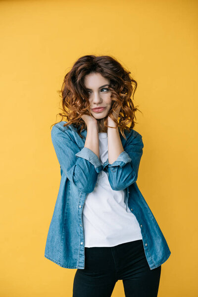 cheerful curly redhead young woman smiling on orange 