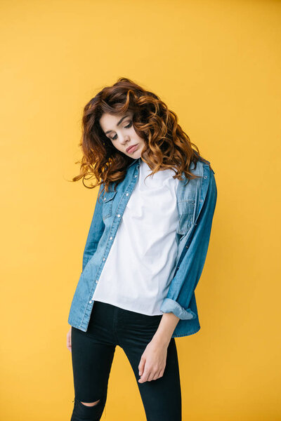 attractive young woman with curly red hair standing on orange 