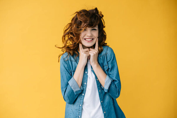 pretty young woman touching cheeks while standing on orange  