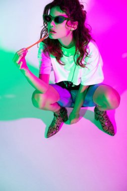 aydınlatma ile pembe oturan kabarcık sakız ile güneş gözlüğü çekici kadın 