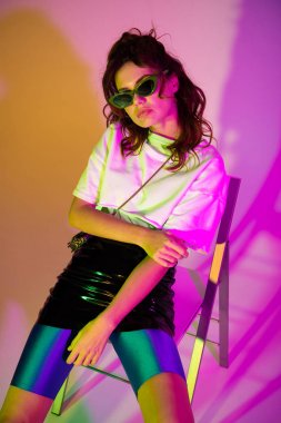 degrade ile mor otururken kameraya bakarak güneş gözlüğü şık kızıl saçlı kız 