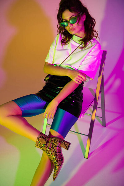 beautiful redhead woman in sunglasses on purple with illumination   