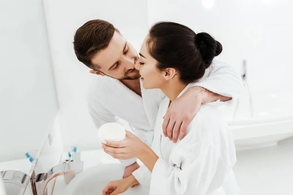 Cheerful Boyfriend Kissing Happy Girl Holding Container Face Cream — Stock Photo, Image