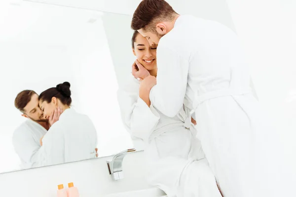 浴室で陽気なブルネットの女性の顔に触れるあごひげの男の選択的な焦点 — ストック写真