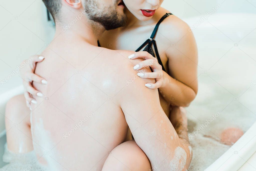 cropped view of man kissing neck and hugging sexy woman in bathtub 