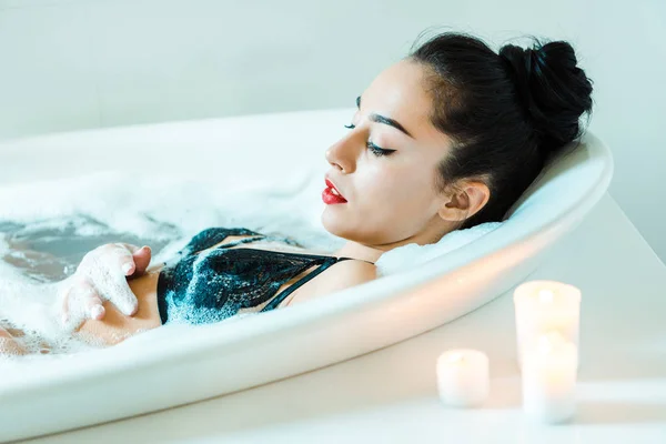 Bela Morena Jovem Deitada Banheira Com Espuma Banho Perto Velas — Fotografia de Stock