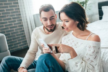 akıllı telefon parmak ile işaret çekici kadın ve mutlu adam yakınında kredi kartı tutarak 