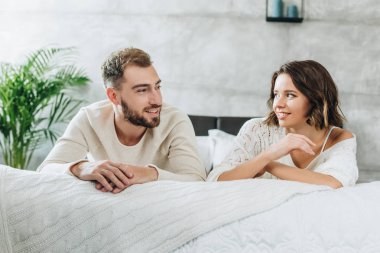 mutlu adam ve çekici kadın yatak odasında birbirlerine bakıyor 