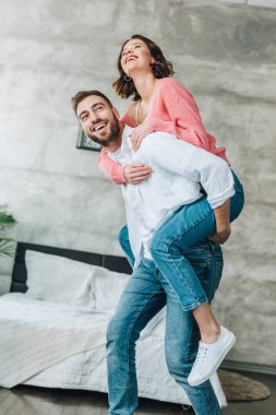 yatak odasında mutlu sakallı adam piggybacking esmer kadın düşük açı görünümü 