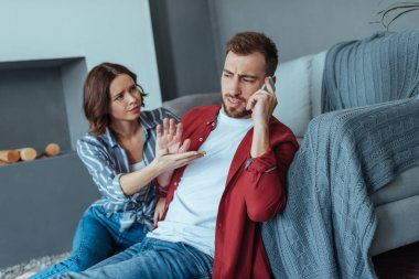 üzgün kadın gesturing ve yakışıklı adam akıllı telefonda konuşurken bakıyor 