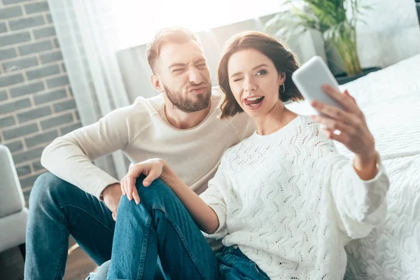 Fröhliche Frau Zeigt Zunge Beim Selfie Mit Bärtigem Mann Hause — Stockfoto