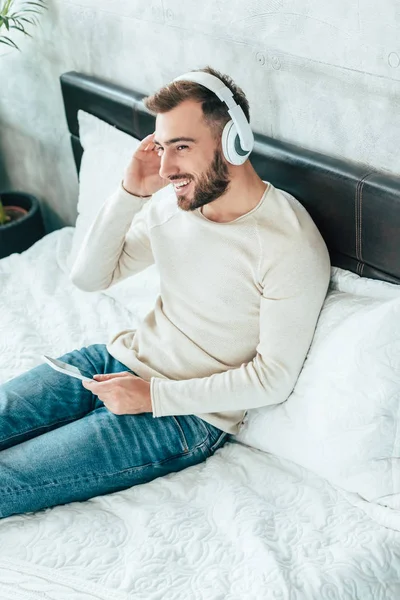헤드폰으로 음악을 들으면서 스마트폰을 사용하는 행복한 수염남자의 오버헤드 — 스톡 사진