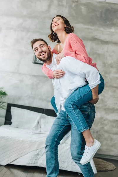 Low Angle View Happy Bearded Man Piggybacking Brunette Woman Bedroom — Stock Photo, Image