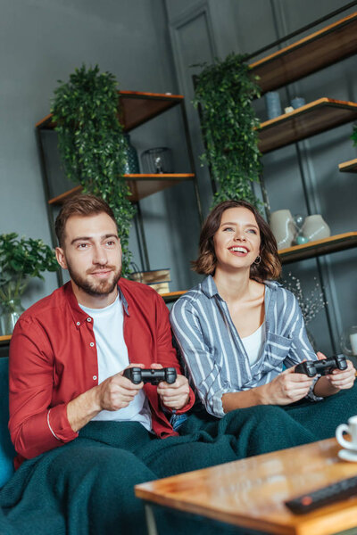 selective focus of handsome man and happy woman playing video came in living room 