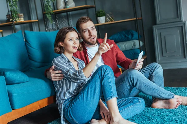 Attractive Woman Pointing Finger Surprised Man Holding Smartphone — Stock Photo, Image