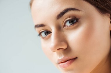 Genç, güzel bir kadın. Parlak dudakları ve gri üzerinde altın göz farı var.