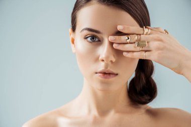 Parlak makyajlı ve altın yüzüklü genç bir kadın. Gözünü griye sakladı.