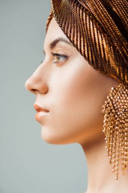 profile of young woman with shiny make up, turban and golden earring isolated on grey clipart