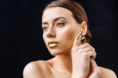 young naked woman with golden makeup and golden paint on finger isolated on black clipart