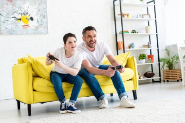 joysticks ile baba ve oğlu Oturma Odasında kanepede Video Oyunu oynarken