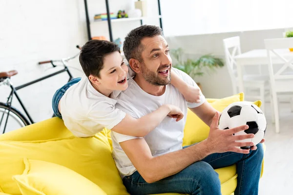 Gelukkige Vader Zoon Kijken Sport Match Bank Met Voetbal Bal — Stockfoto