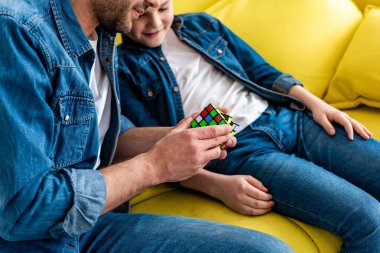 kanepede otururken oyuncak küp ile oynayan baba ve oğul kısmi görünümü 