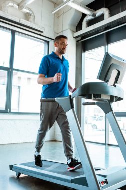 handsome man running on treadmill at gym clipart