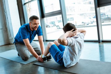 baba spor salonunda egzersiz oturup oğlu yardım