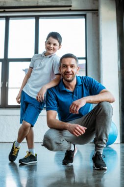 gülümseyen baba ve oğul spor merkezinde kameraya bakıyor
