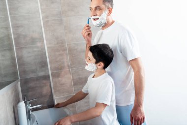 banyoda jilet ile tıraş baba yakınında yüzünde tıraş kremi ile oğlu