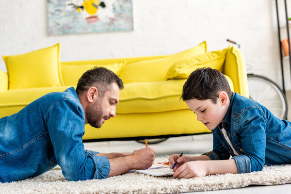 father and son lying on carpet and drawing in Living Room