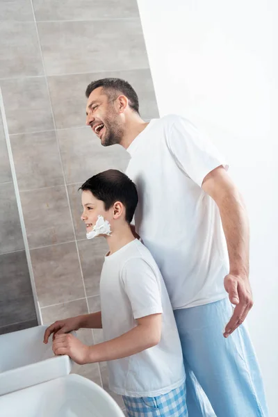 Sonriente Hijo Con Crema Afeitar Cara Cerca Feliz Padre Baño — Foto de Stock