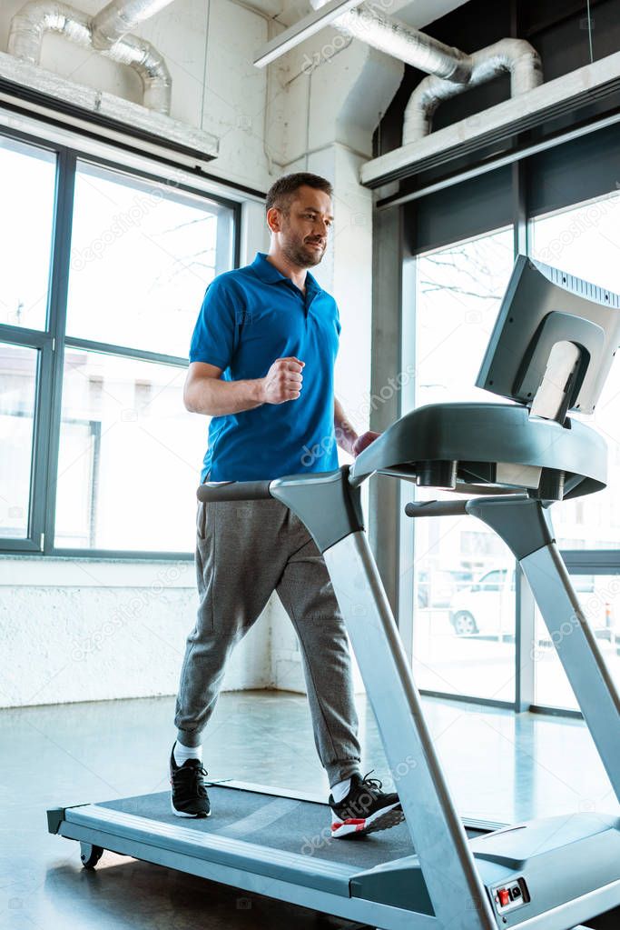 handsome man running on treadmill at gym