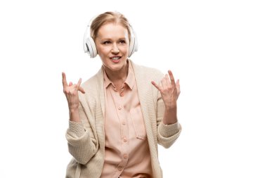 kulaklık orta yaşlı kadın müzik dinlerken ve beyaz izole rock işaretleri gösteren