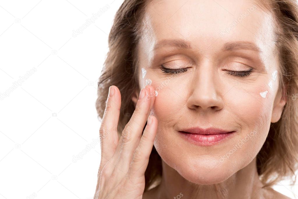 mature woman applying cosmetic cream on face Isolated On White