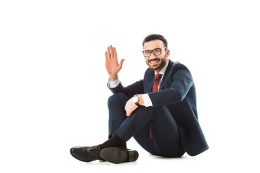 beyaz arka plan üzerinde otururken merhaba jest gösteren neşeli işadamı