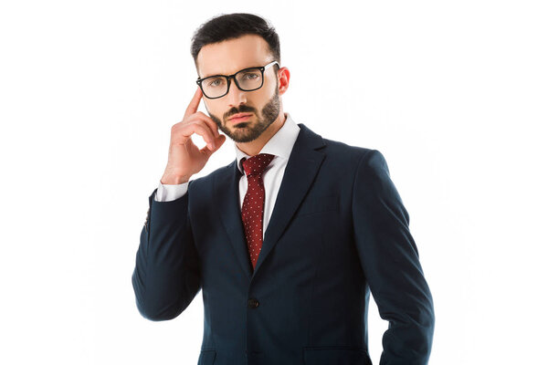 thoughtful businessman holding hand near head and looking at camera isolated on white