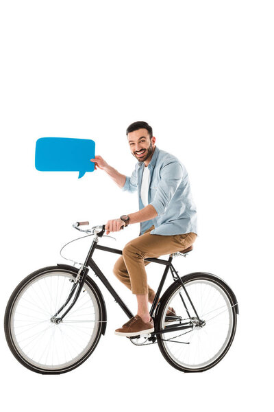 Улыбающийся красивый мужчина держит пузырь речи и ездит на велосипеде, изолированном на белом
