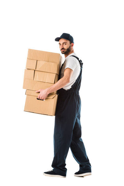 confident delivery man carrying cardboard boxes and looking at camera isolated on white